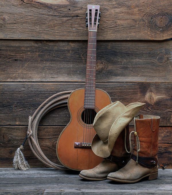 a cowboy hat, boots and a guitar are sitting on a bench