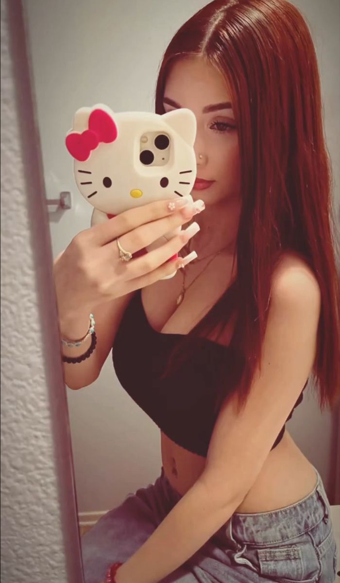 a woman taking a selfie in front of a mirror with her hello kitty phone