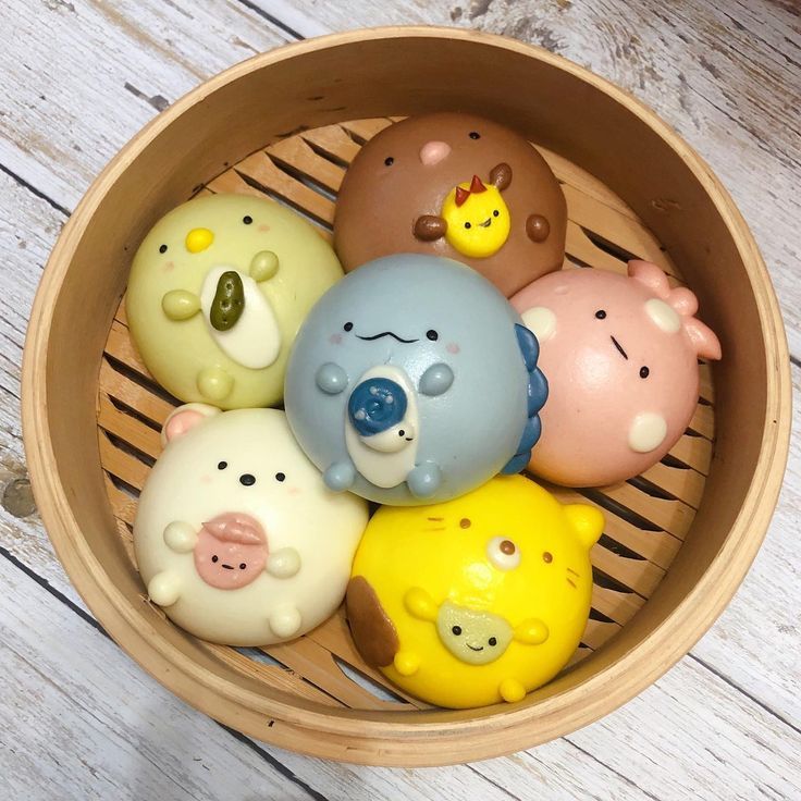 a wooden basket filled with different colored plastic animals on top of a white wood floor