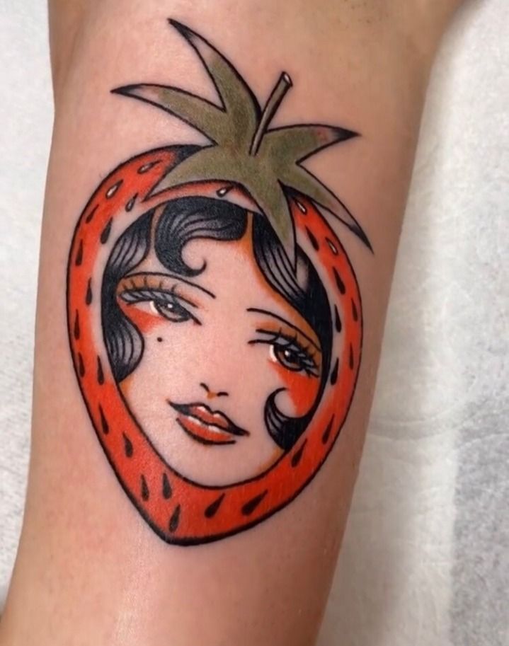 a woman's arm with a tattoo design on it, featuring a red tomato