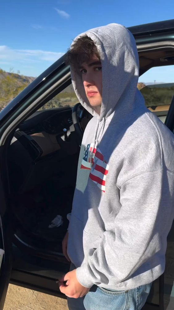 a young man sitting in the back of a car with his hands on his hips