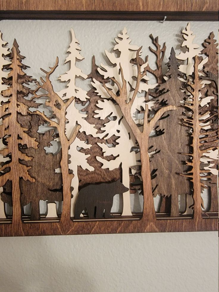 a wooden cutout of trees and animals in the woods on a wall with a white background