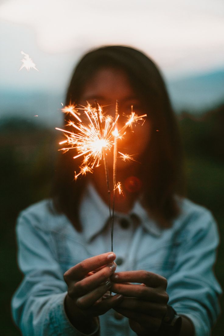 a woman holding a sparkler in her hands