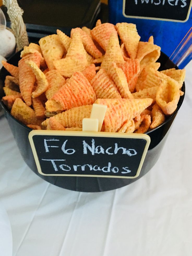 a bowl filled with cheetos sitting on top of a table next to a sign