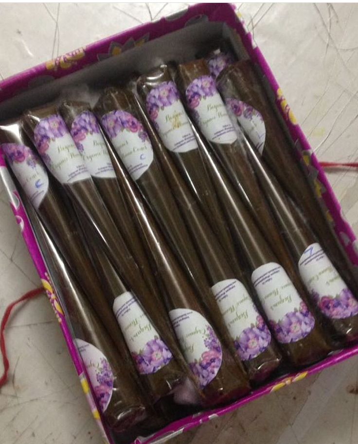 six chocolate straws in a pink box with purple flowers on the top and bottom