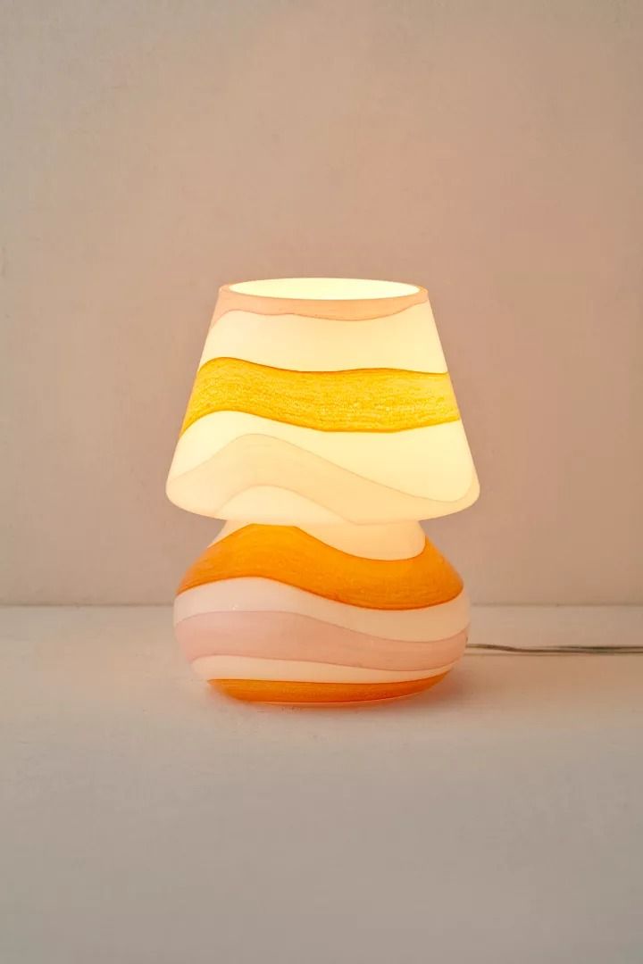 an orange and white lamp sitting on top of a table next to a light bulb