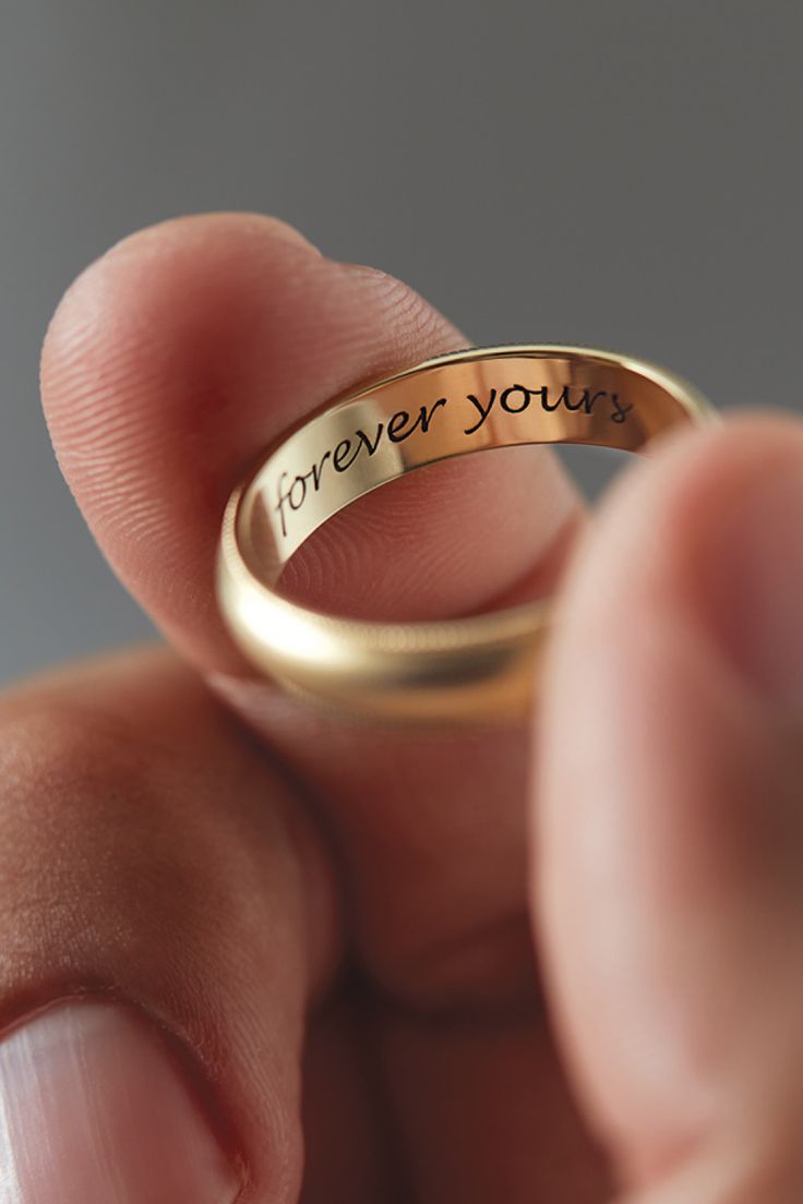 a person holding a gold ring with the words forever you's engraved on it