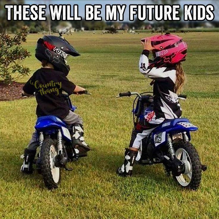 two children on small motorcycles in the grass