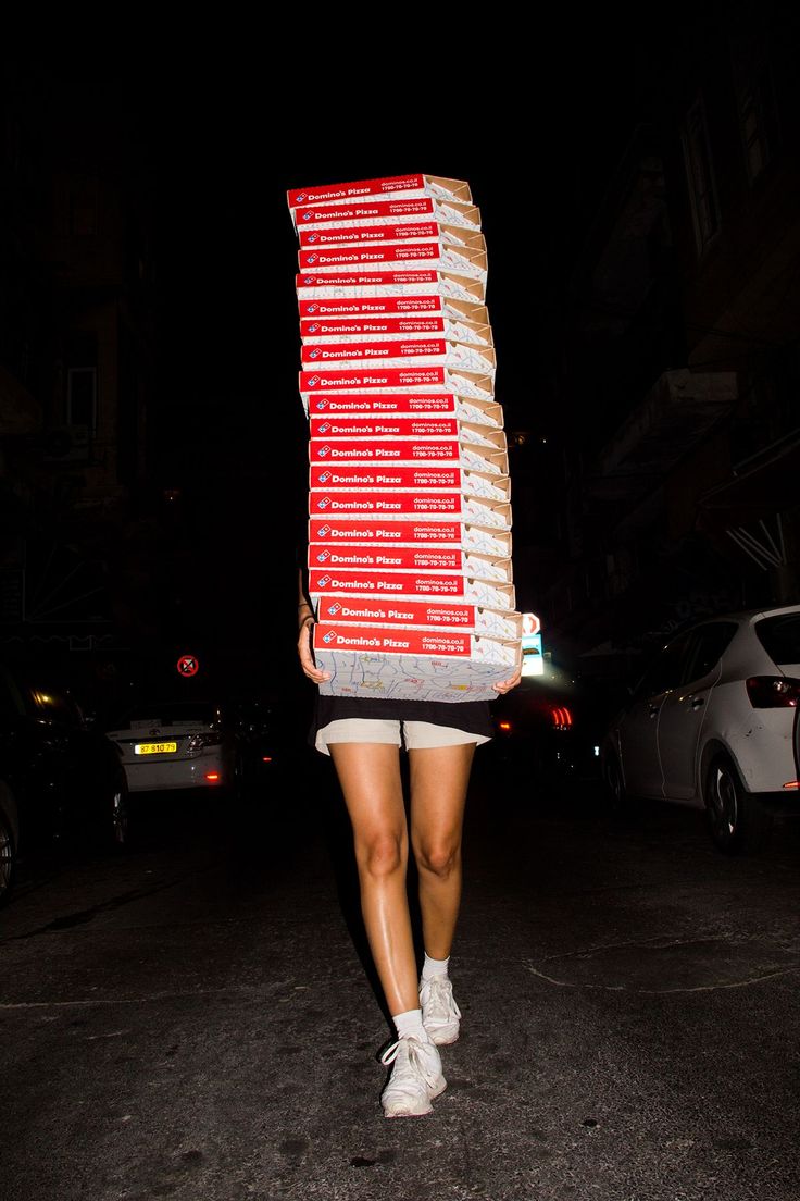 a woman walking down the street with a large box on her head and shoes on