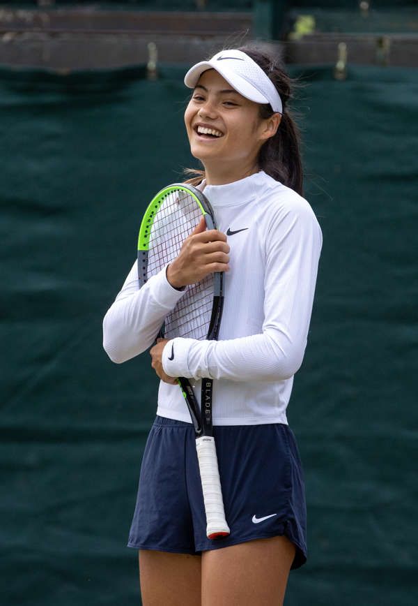 a young woman holding a tennis racquet on top of a tennis ball court