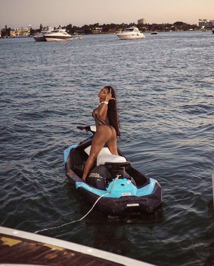 a woman riding on the back of a blue and black jet ski in the water