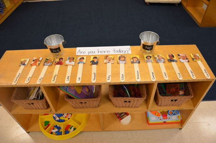 a wooden table topped with lots of books and cups filled with pencils next to bins