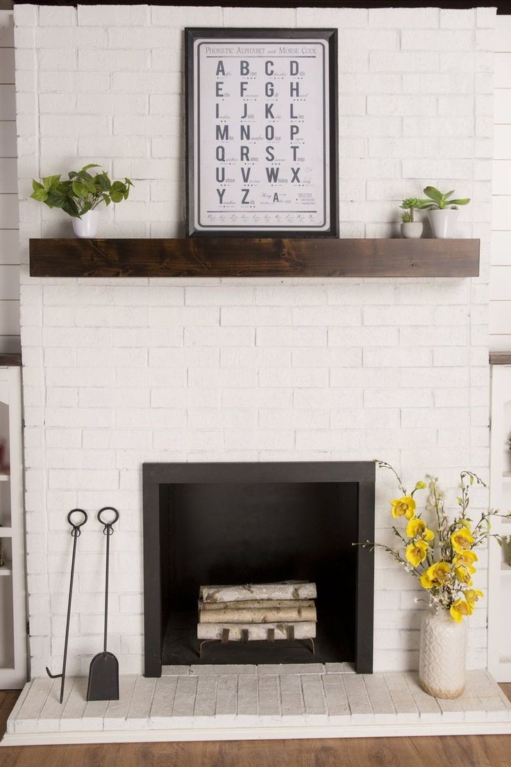 a white brick fireplace with yellow flowers and books