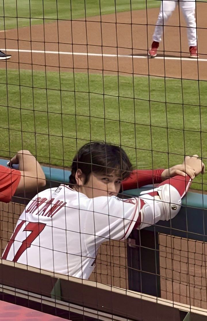 a baseball player sitting in the dugout with his hands on his hips and arms behind his head