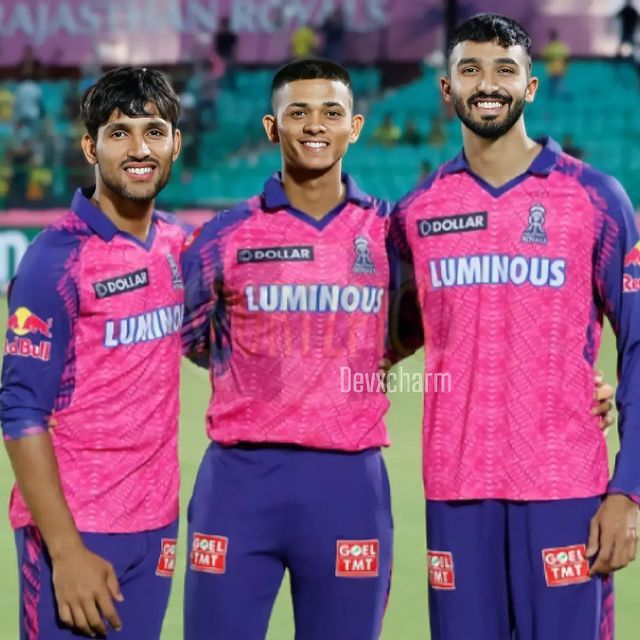 three men standing next to each other on a field wearing purple uniforms and smiling at the camera