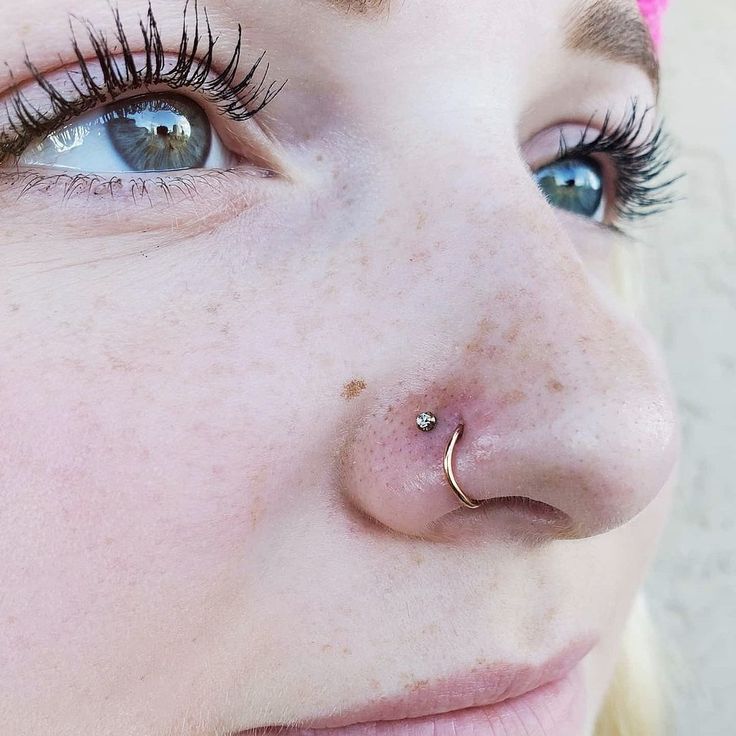 a close up of a person with piercings on their nose