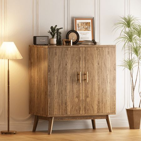 a wooden cabinet sitting next to a lamp on top of a hard wood floored floor