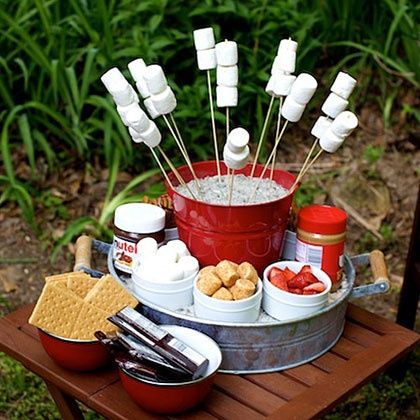 an outdoor picnic with marshmallows, hotdog sticks and ketchup