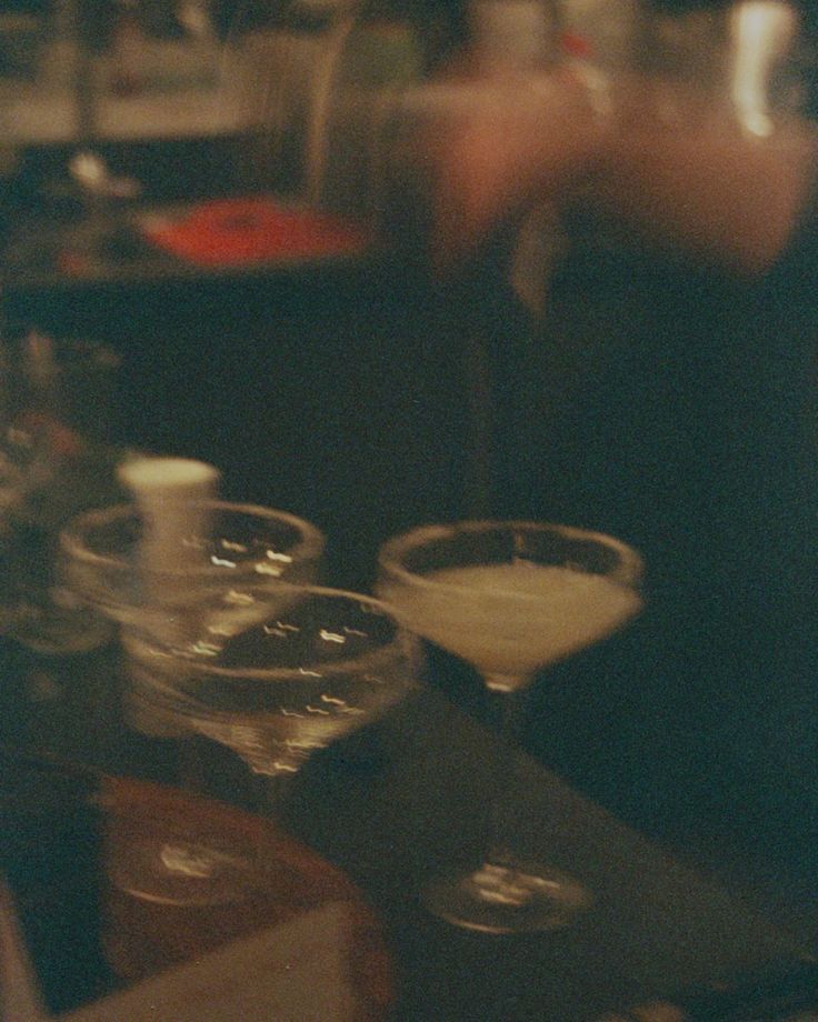 a blurry image of some glasses on a table with food and drinks in them