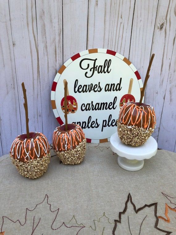 three caramel apples sitting on top of a white plate next to a sign that says fall leaves and caramel cakes pies