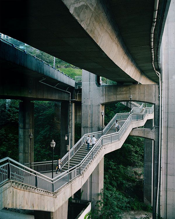 people are walking up and down the stairs under an overpass with trees in the background