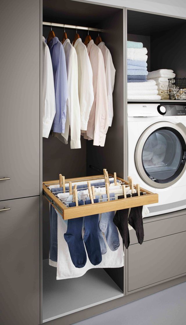 a washer and dryer in a small room with clothes hanging on the rack