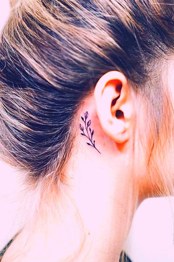 a woman's ear with a small flower tattoo on her left behind the ear