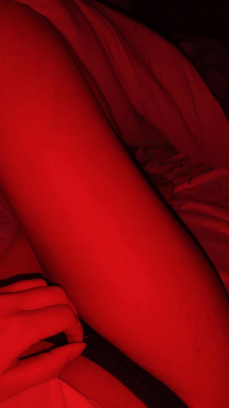 a person laying in bed with red light on their leg and arm, under the covers