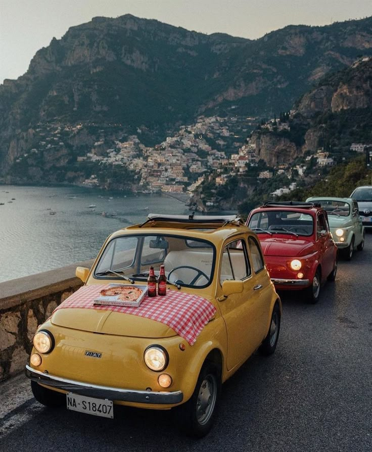 an old yellow car is parked on the side of the road