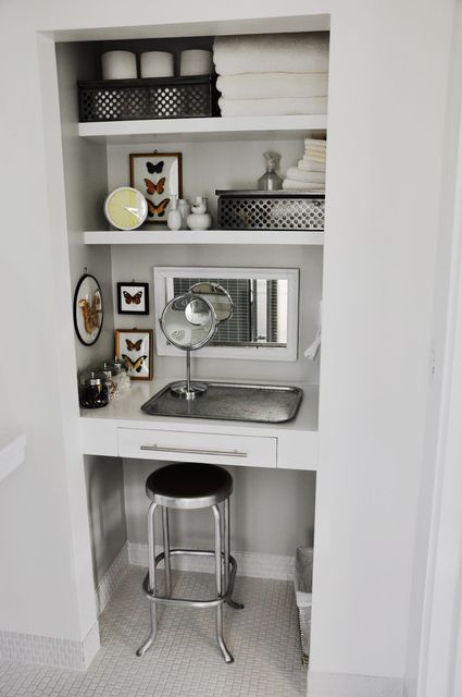 a bathroom with white walls and shelves filled with items