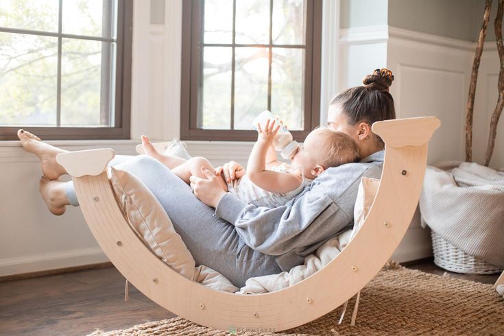 a woman holding a baby while sitting in a hammock chair with her feet up