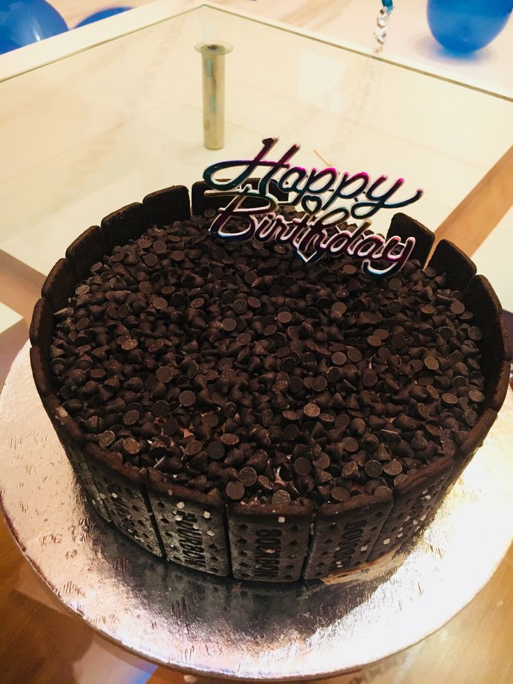 a birthday cake with chocolate chips and happy birthday written on the top is sitting on a table