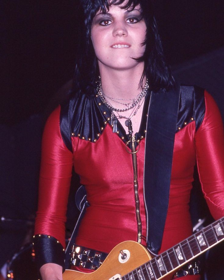 a woman in red and black outfit holding a guitar