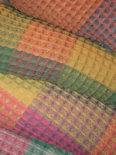 a multicolored blanket sitting on top of a bed