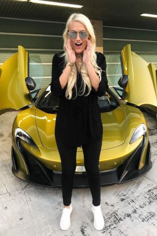 a woman standing in front of a yellow sports car with her hands on her face