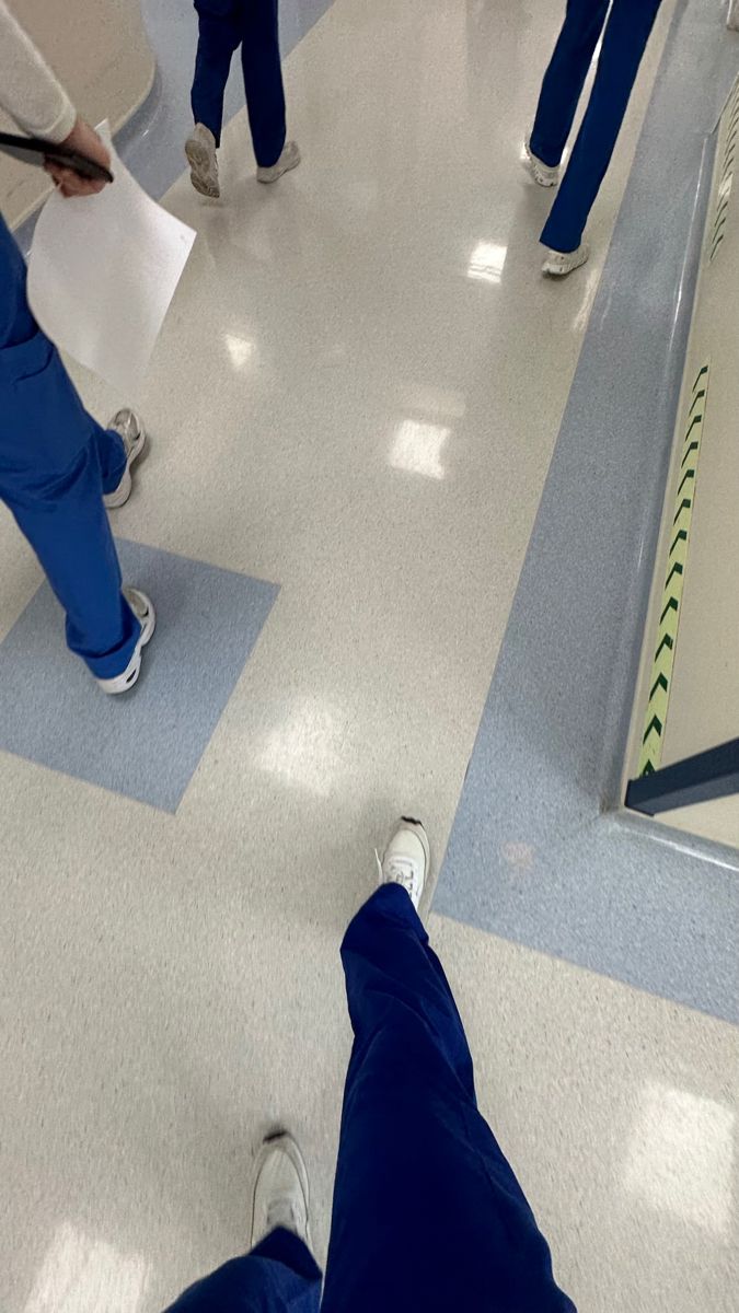 several people in scrub suits are walking down an airport hallway with their feet on the ground