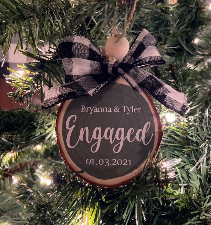 a wooden ornament hanging from a christmas tree with the name engaged on it