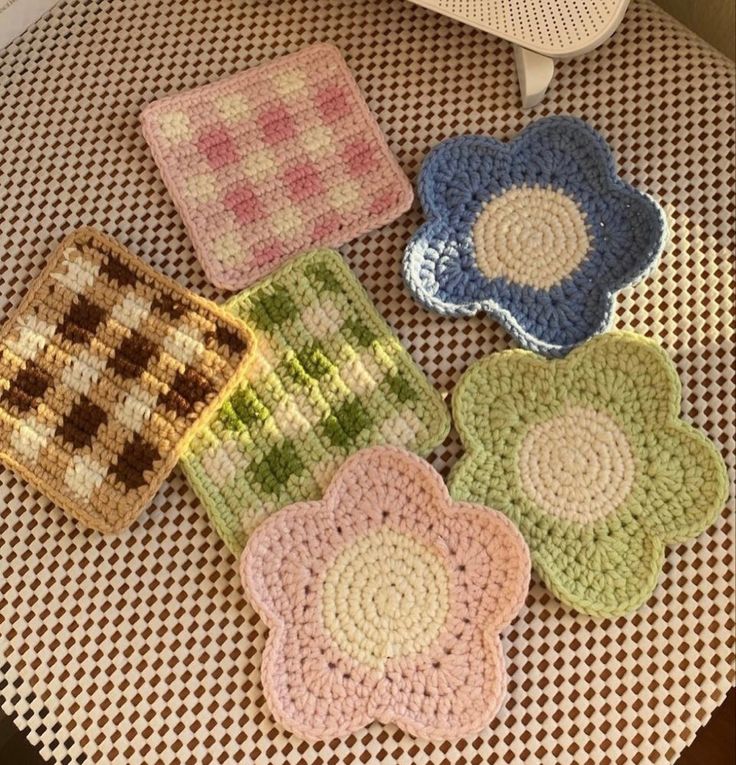 four crocheted flower coasters sitting on top of a brown and white chair