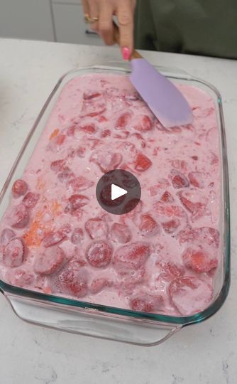 a glass dish filled with ice cubes on top of a counter next to a person's hand