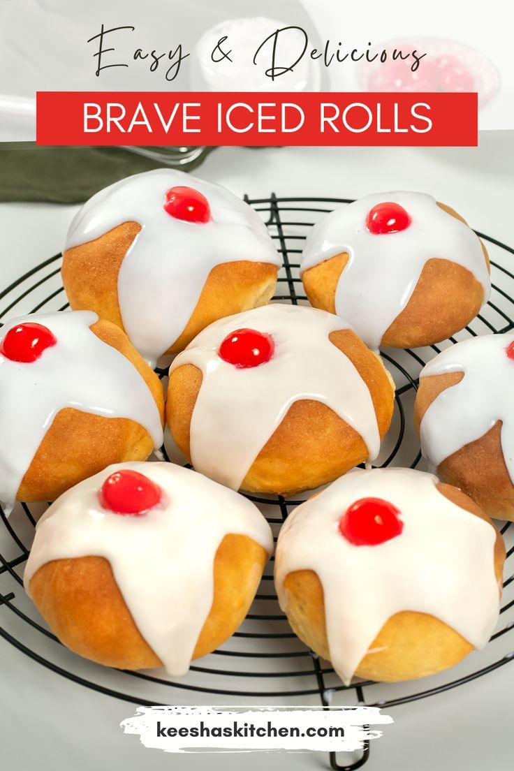 several pastries with white icing and cherries on a cooling rack