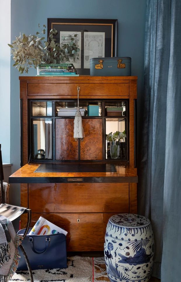 an old wooden dresser sitting in a living room next to a blue wall with pictures on it