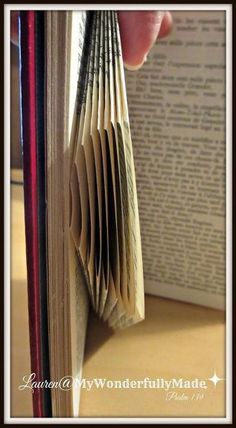 an open book that is sitting on a table next to a person's hand