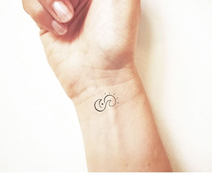 a woman's wrist with a small tattoo on the left side of her arm