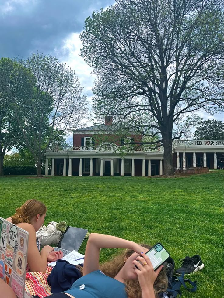 two people laying on the grass in front of a house