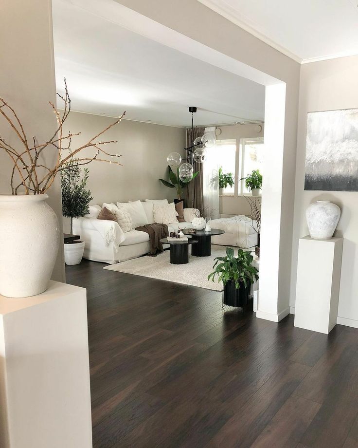 a living room filled with white furniture and potted plants on top of hard wood floors