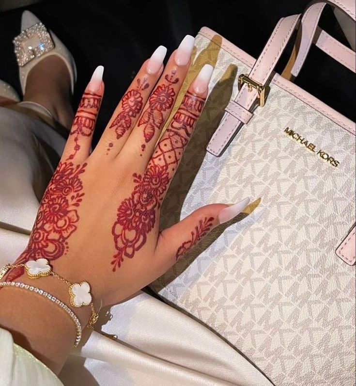 a woman's hand with hendix on it next to a white purse