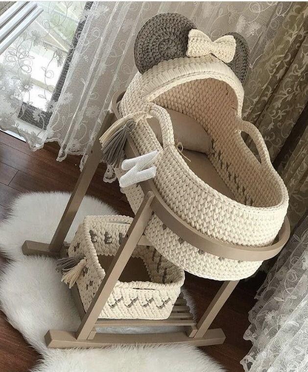 a crocheted baby's cradle with a teddy bear on top and other items