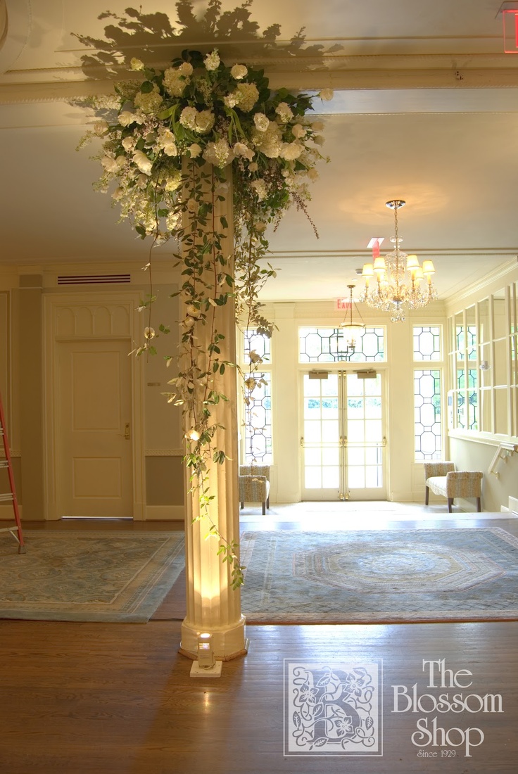 a tall vase with white flowers on top of a wooden floor next to a doorway