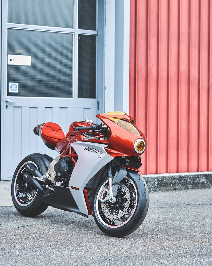 a red and silver motorcycle parked in front of a building