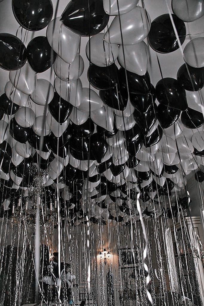 many balloons are hanging from the ceiling in an open room with black and white decor